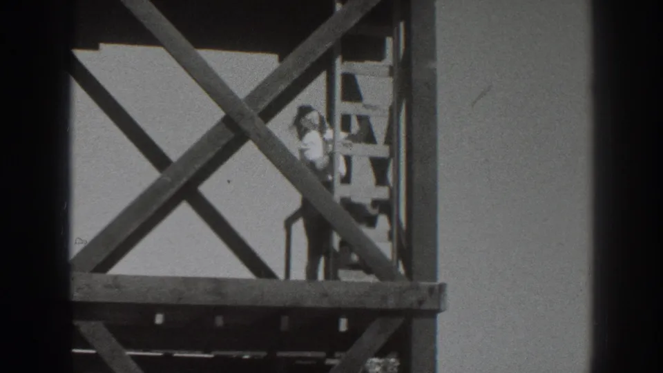 1937 Sacramento home-movie frame showing the tower supports and a person climbing down or standing on the ladder.