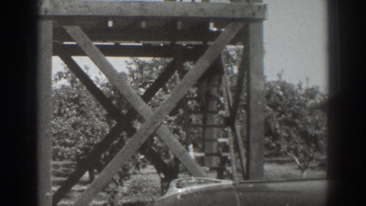 1937 Sacramento frame showing the tower supports and ladder with trees behind and the partial roofline of a vehicle at lower right.