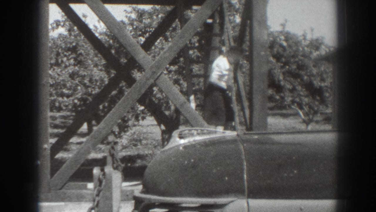 1937 Sacramento frame showing a woman at the lower part of a wooden staircase, with orchard trees and a parked car in view.