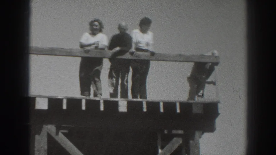 1937 Sacramento home-movie frame showing adults gathered at a railing on a raised wooden platform against open sky.