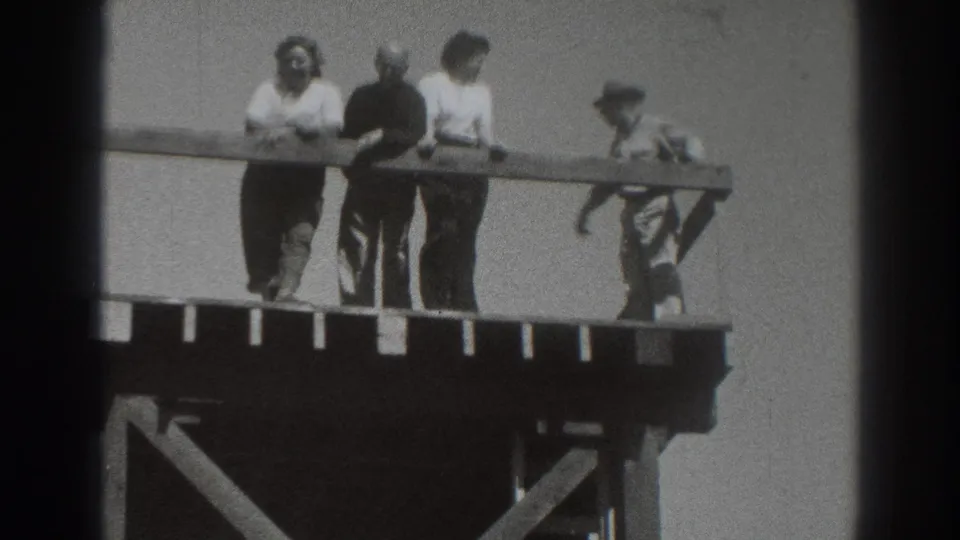 1937 Sacramento home-movie frame showing a group at a wooden platform railing, with a smaller figure near the right side.