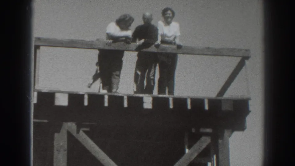 The group stays close to the wooden overlook rail, with one person partly obscured and others looking outward or downward.