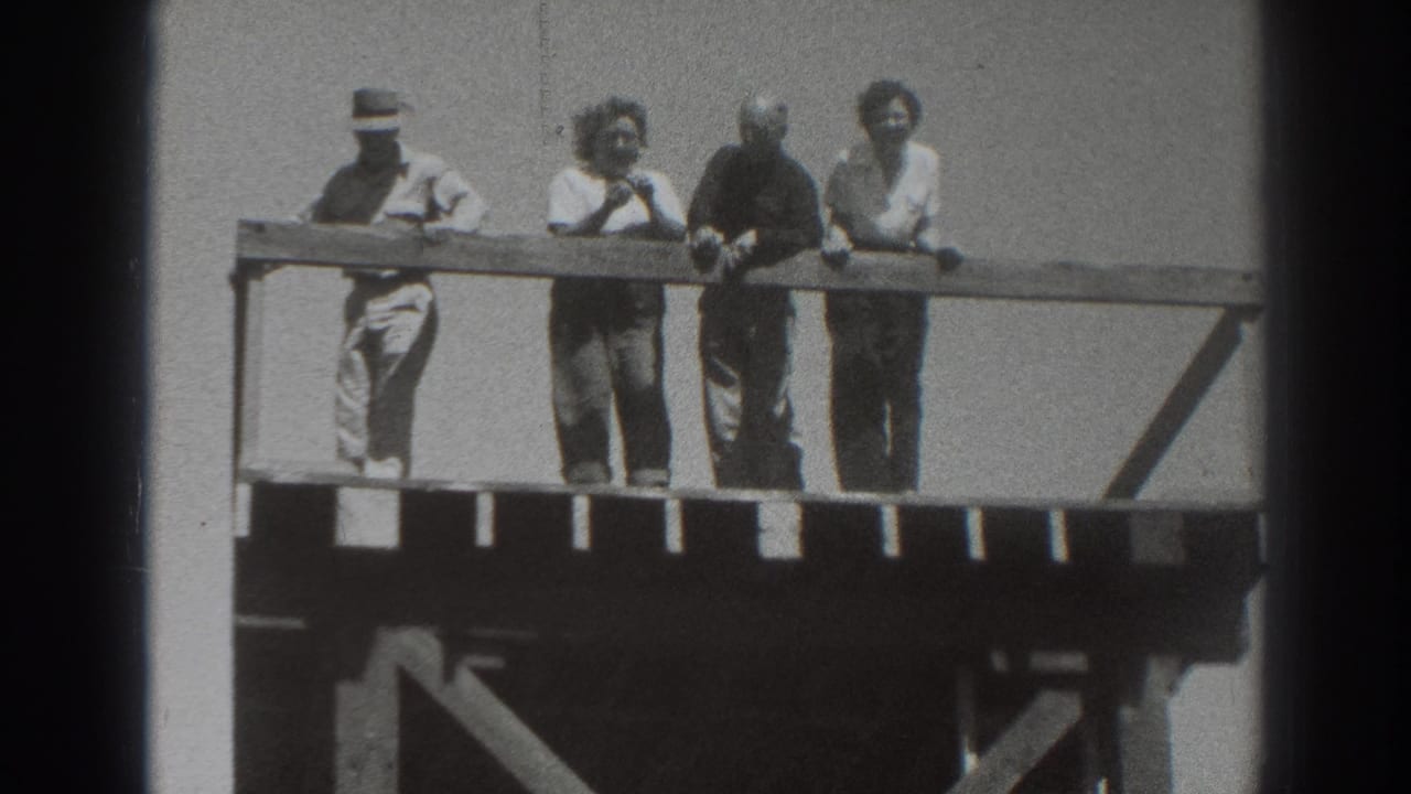 Four adults remain at the railing on an elevated wooden platform in Sacramento, with the left figure in a hat and others facing outward.