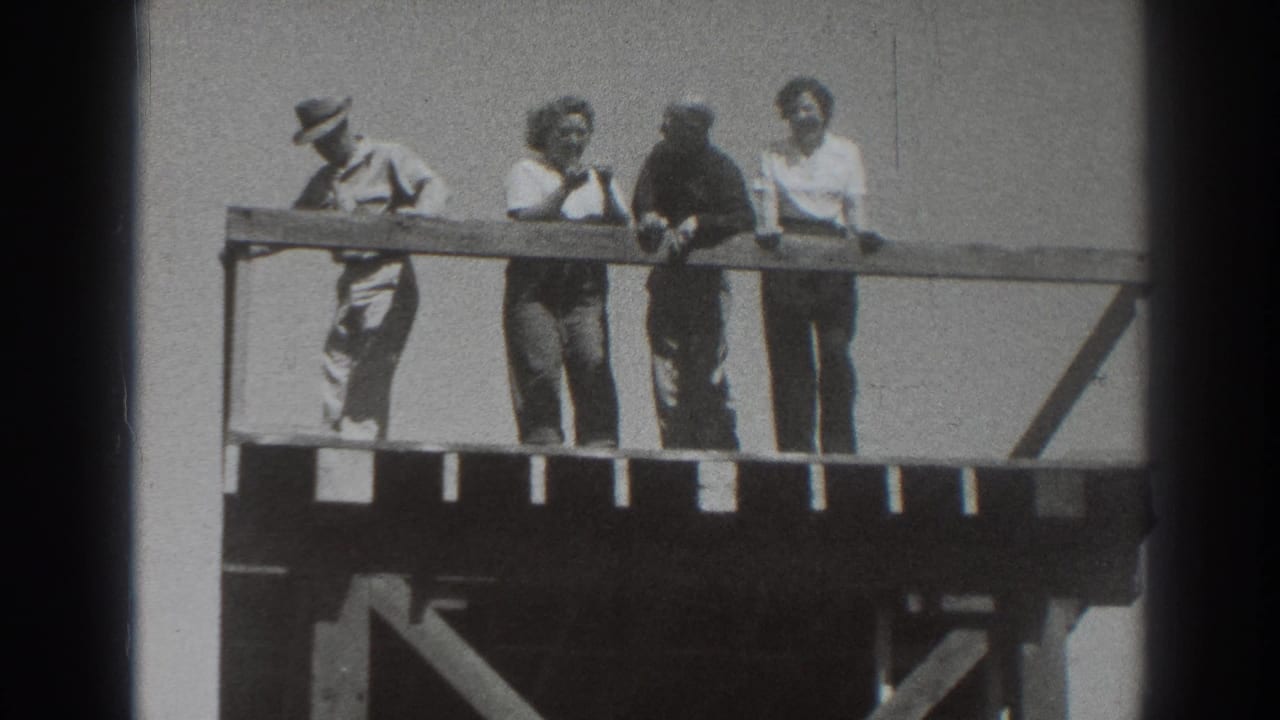 On the wooden platform, the man at left bends forward while three other adults stand near the railing in bright 1937 Sacramento footage.
