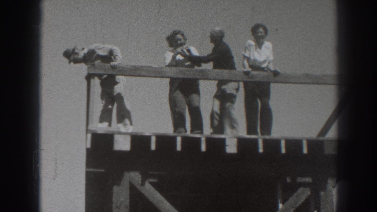 In 1937 Sacramento home-movie footage, several adults gather on a wooden deck as one leans far over the rail.
