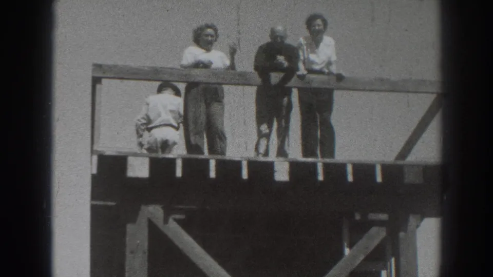 Adults on an elevated wooden deck in 1937 Sacramento face the camera while another figure crouches or bends near the rail.