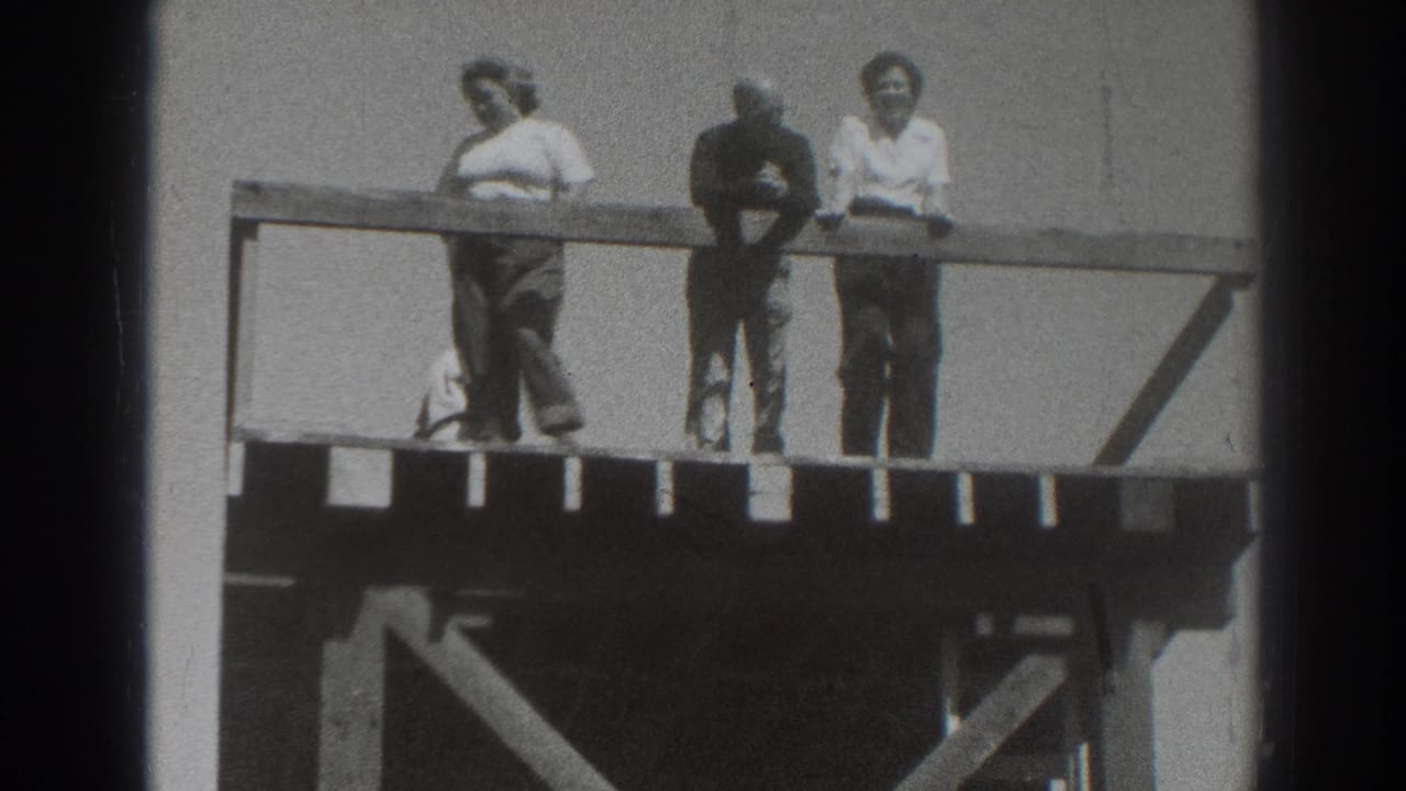 Three adults remain at the railing of a wooden deck in Sacramento, framed by open sky and visible 8mm film edges.