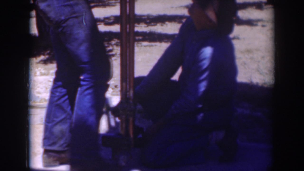 A Sacramento 1937 frame shows a kneeling man handling the base of a pole or pipe with a second man standing nearby.
