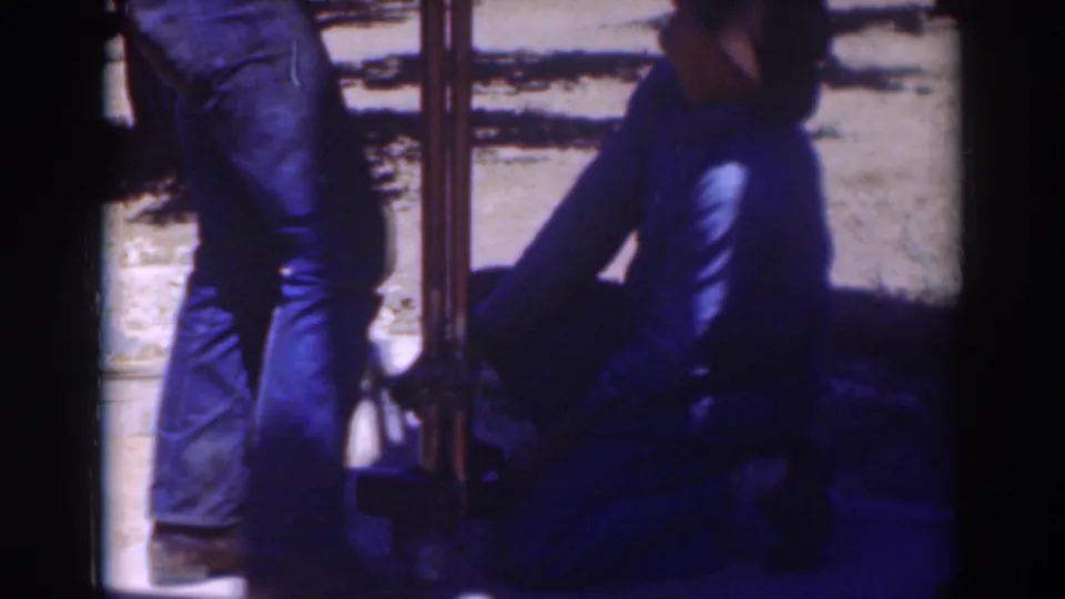 A Sacramento 1937 frame shows a kneeling man handling the base of a pole or pipe with a second man standing nearby.