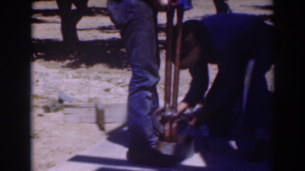 The closing frame shows a crouching man working at the tool base as another man stands nearby in the Sacramento orchard.