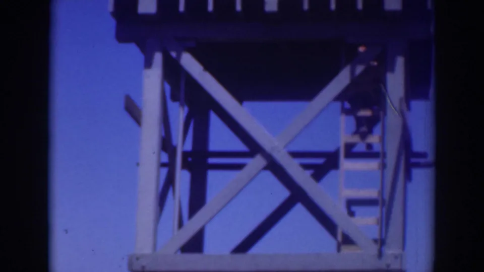 In 1937 Sacramento footage, a worker appears on a wooden ladder beside an elevated tank and braced support structure.