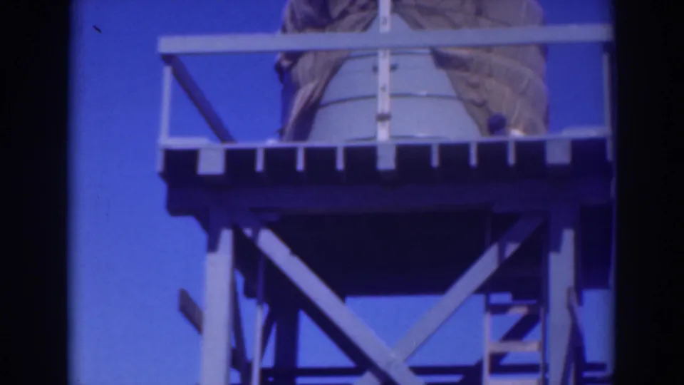 The upward view shows the elevated tank, surrounding rail, and heavy cross-braced supports in 1937 Sacramento home-movie footage.