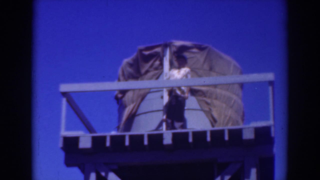 Person remains on the railed platform near the covered object.