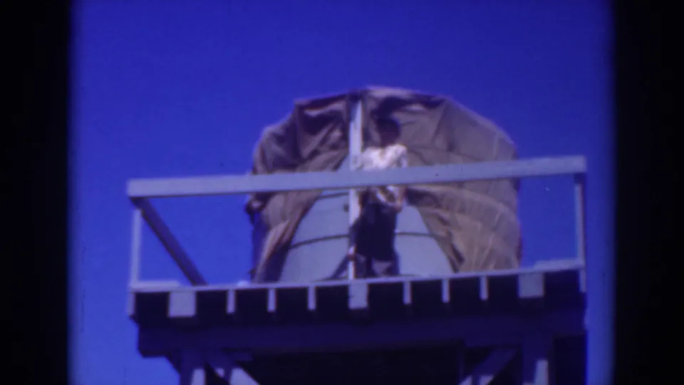 The person appears centered on the elevated Sacramento platform, partly obscured by railing, with the large covered object behind them.