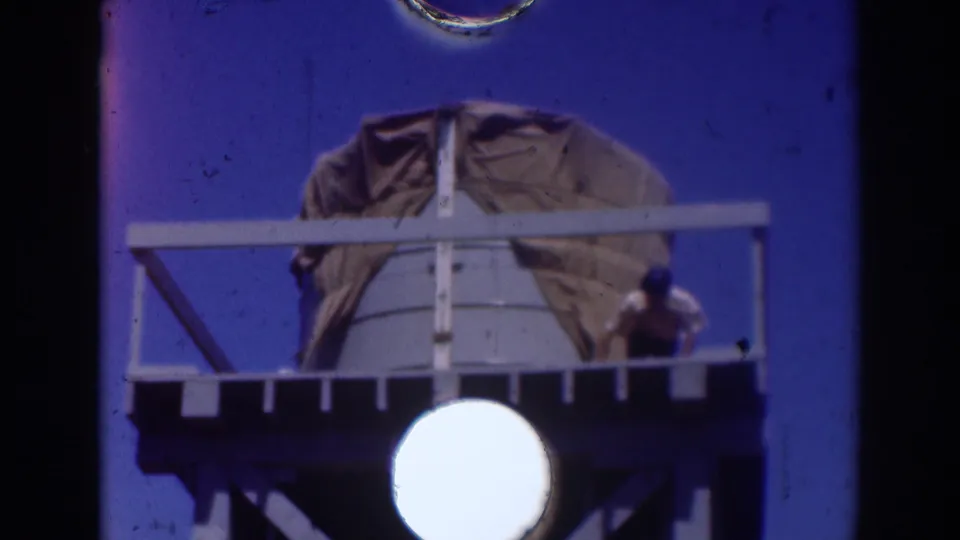 At the end of the clip, the worker is near the right railing of the elevated Sacramento water-tank platform, with film dust and gate marks visible.