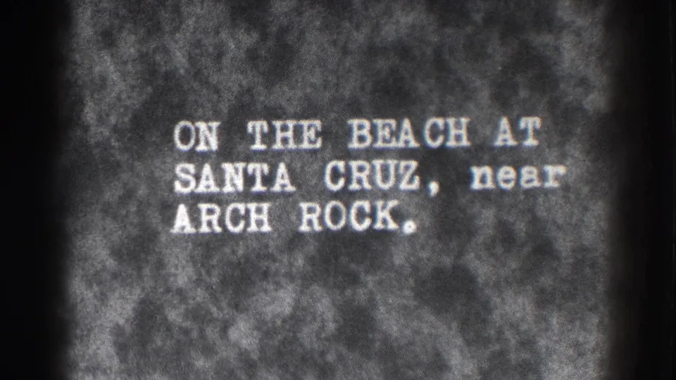 Black-and-white 8mm title card identifying the Santa Cruz beach setting near Arch Rock.