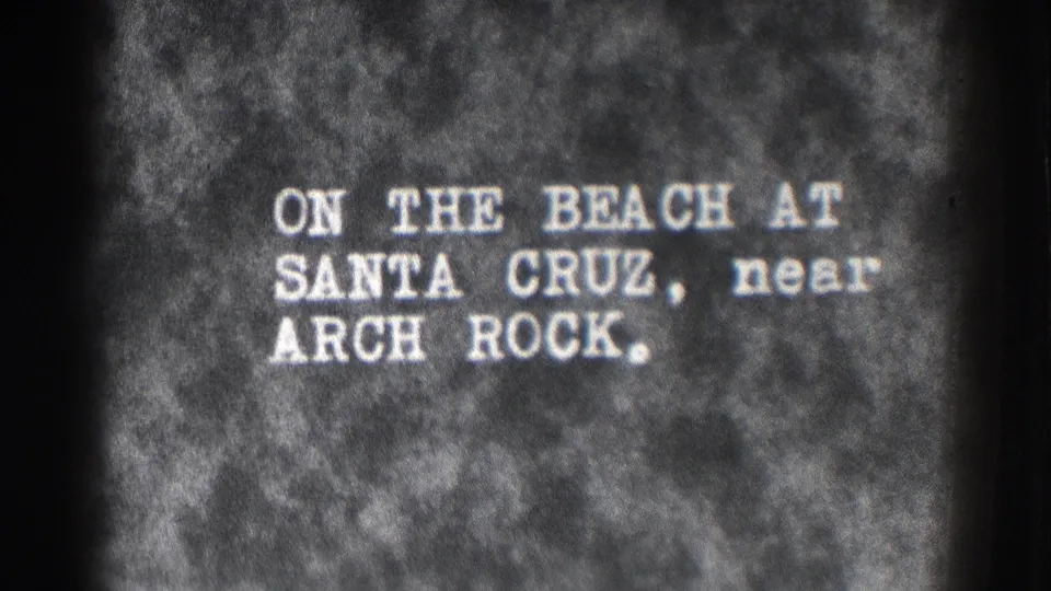 Black-and-white title-card frame repeating the Santa Cruz beach and Arch Rock identification.