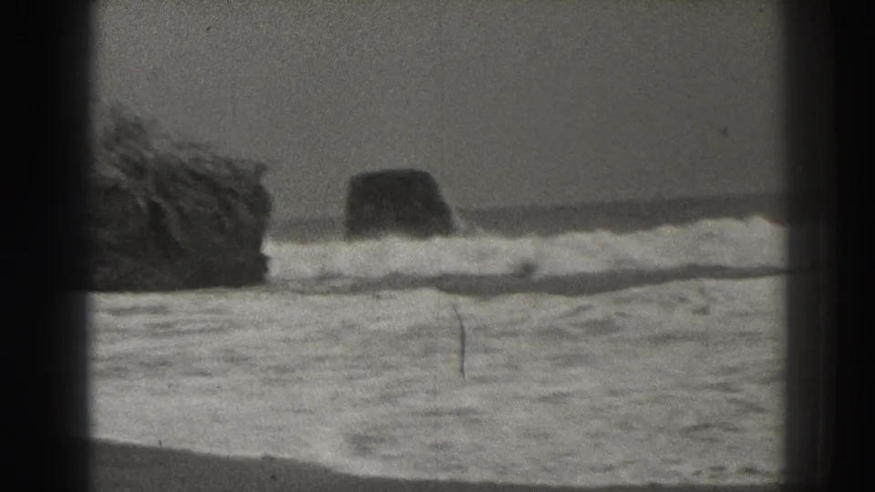 Black-and-white 8mm view of Santa Cruz surf washing around offshore rocks in 1937.