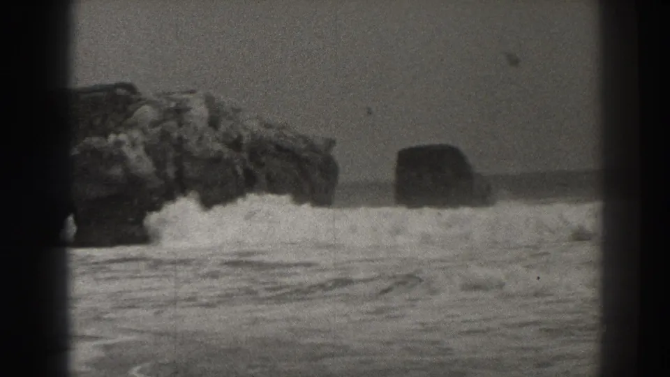 1937 8mm Santa Cruz shoreline view with jagged rocks at left and surf rolling across the frame.