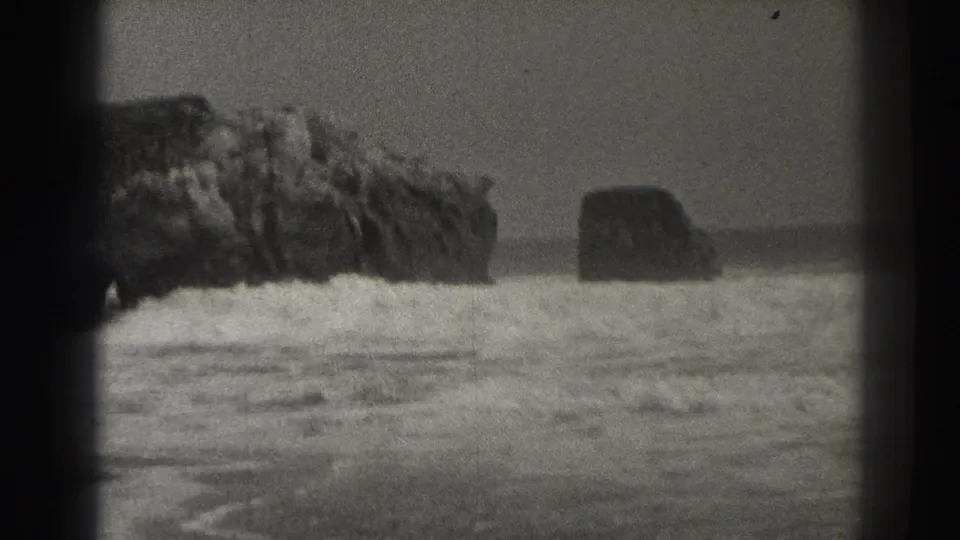 1937 Santa Cruz beach footage showing waves breaking around large offshore rocks in soft black-and-white 8mm framing.