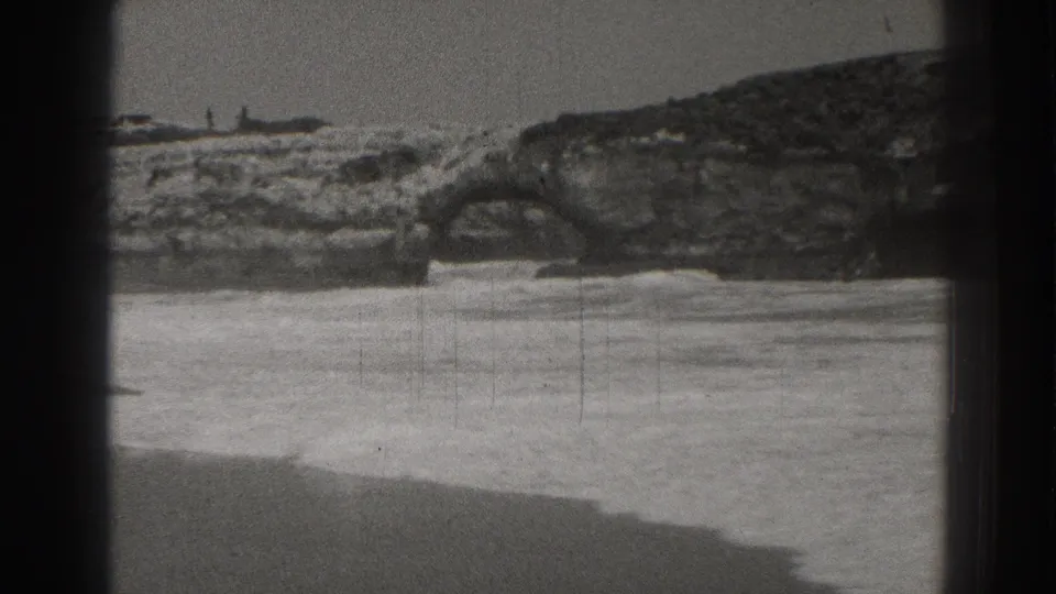 Santa Cruz beach surf and coastal rock formations are seen in a grainy 1937 8mm home-movie frame.