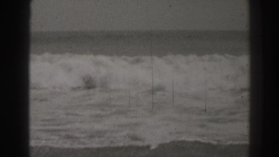 Black-and-white 1937 Santa Cruz beach footage showing surf breaking across the frame with dark 8mm borders and film scratches.