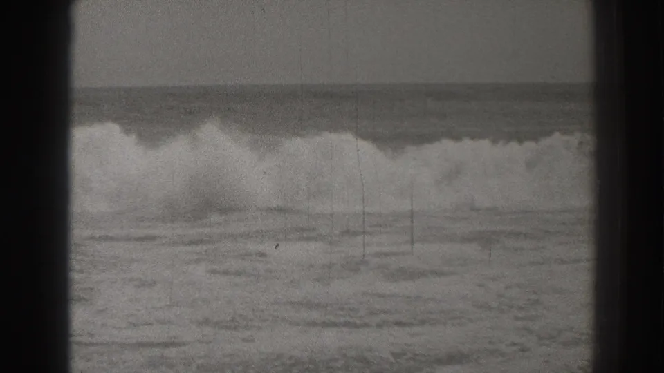 1937 Santa Cruz 8mm frame showing a broad surf break with foam rolling toward the beach.