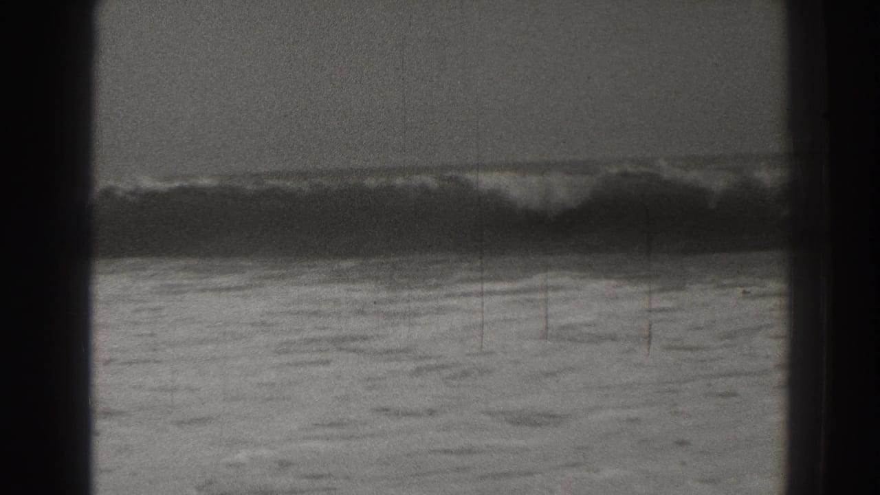 Breaking ocean waves seen through dark vertical framing.