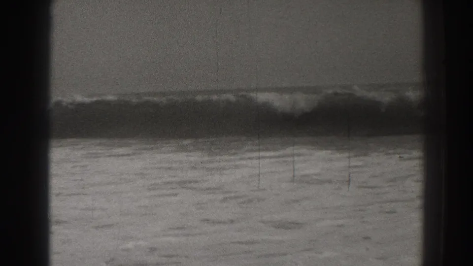 Black-and-white 1937 Santa Cruz surf footage showing waves breaking offshore through a dark framed opening.