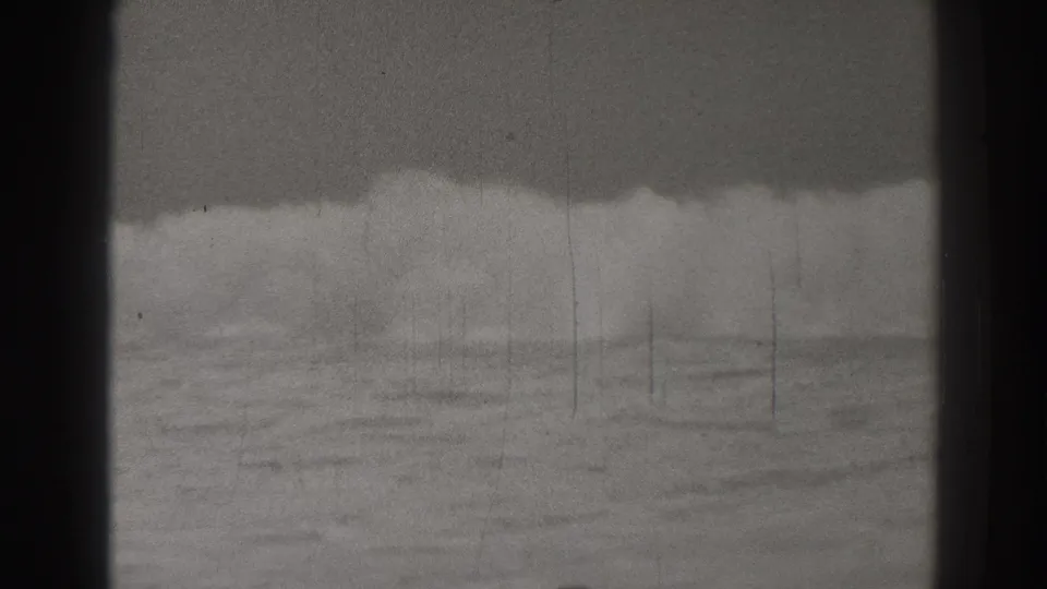 A broad wave breaks across the Santa Cruz shoreline area in grainy black-and-white 8mm footage.