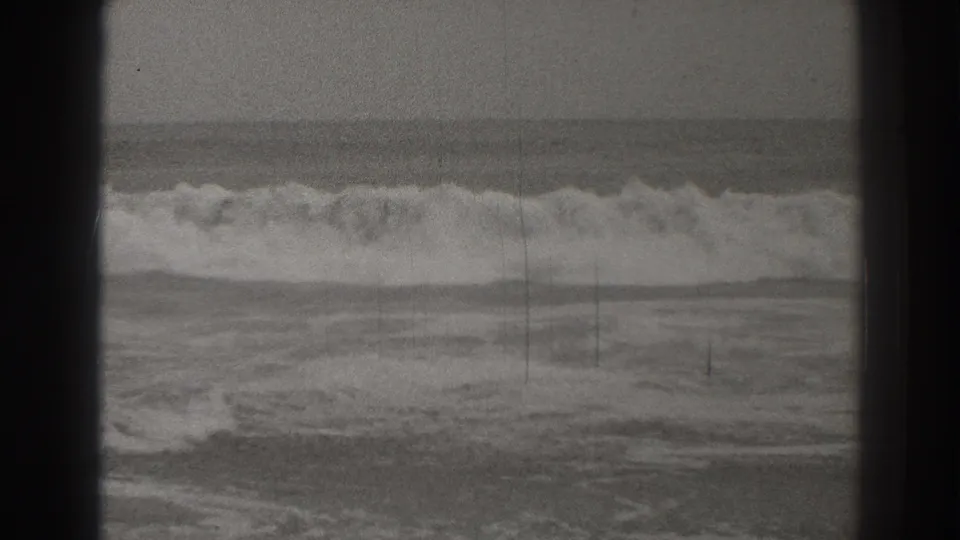 Black-and-white 1937 Santa Cruz home-movie frame showing surf breaking near the shoreline with grain and dark 8mm frame edges.