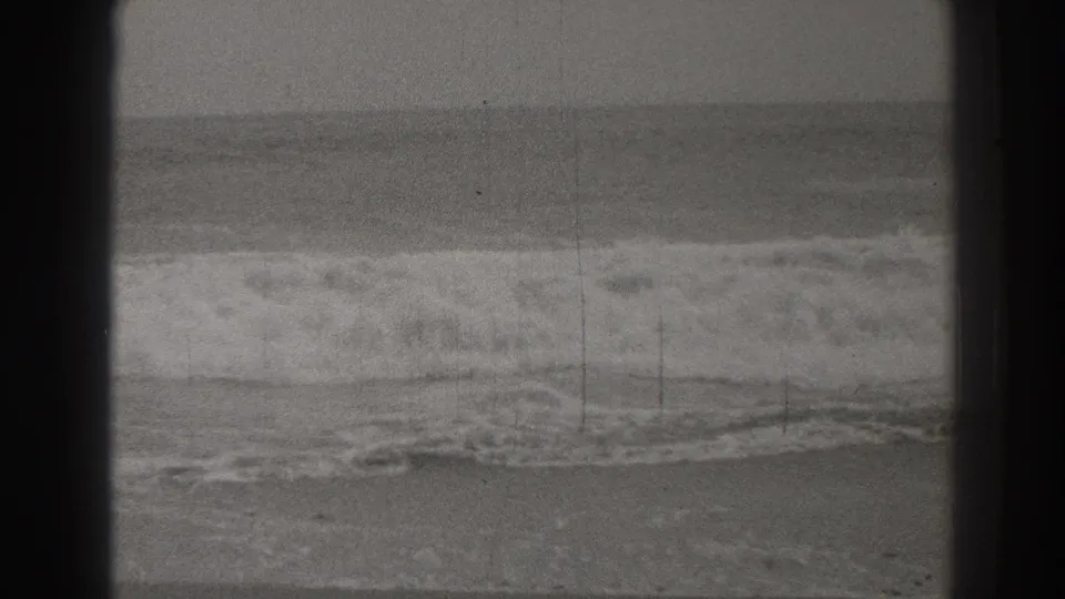Santa Cruz shoreline footage shows low foamy waves moving toward shore, with visible grain, scratches, and dark 8mm frame edges.