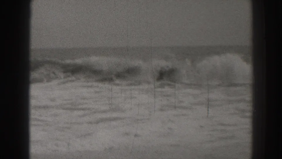 A 1937 Santa Cruz shoreline frame showing a broad wave crest moving toward wet sand, framed by dark 8mm borders and scratches.