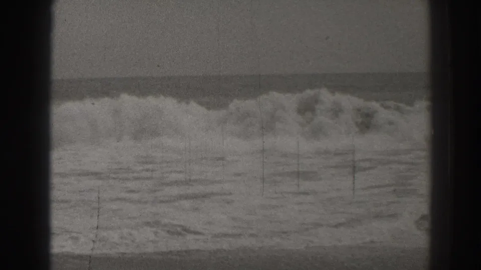 Final 1937 Santa Cruz 8mm frame with heavy surf breaking near shore, muted sky, grain, and dark edge framing.