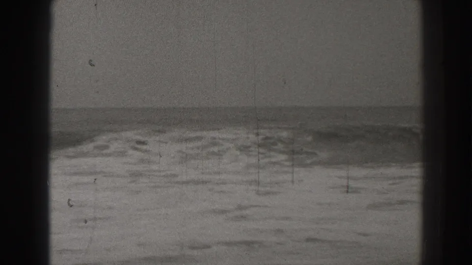 1937 Santa Cruz 8mm frame showing waves rolling toward shore under an overcast sky, with visible grain and scratches.