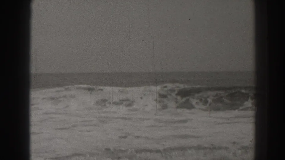 Black-and-white 1937 Santa Cruz shoreline view with a curling wave, foam, horizon, and physical film wear.