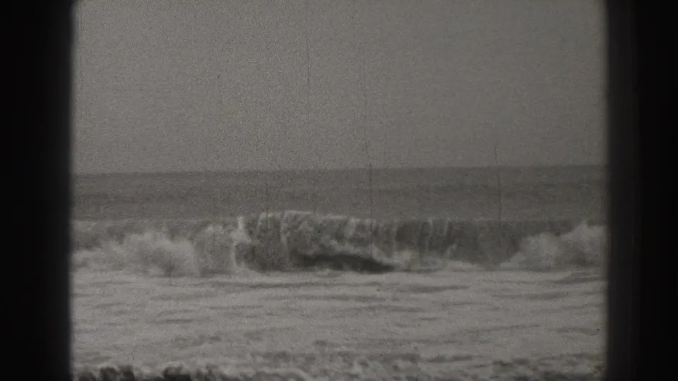 1937 Santa Cruz home-movie frame of a close breaking wave, foamy surf, and a soft ocean horizon on black-and-white 8mm film.