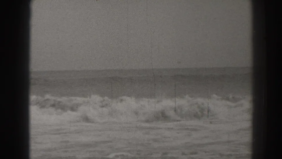 Black-and-white 8mm view of Santa Cruz surf in 1937, with foam moving across the lower frame and a steady horizon beyond.