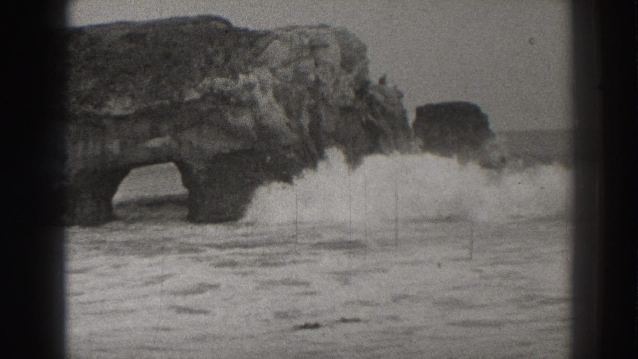 Rock arch and sea stack with waves breaking across the foreground.