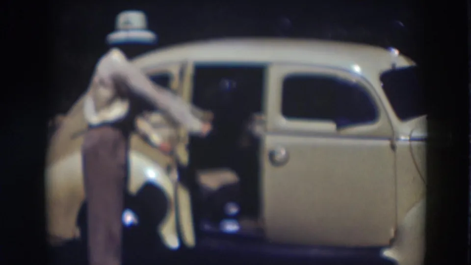 In the 1937 Truckee clip, the man reaches for the open door of a cream-colored car after the passenger has entered.