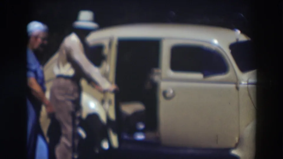 Final 1937 Truckee frame shows the man at the open car door with another adult partly visible behind him.