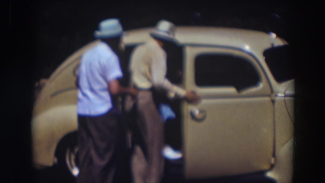 The 1937 Truckee home movie shows two hat-wearing men beside the open rear door as a passenger enters the car.