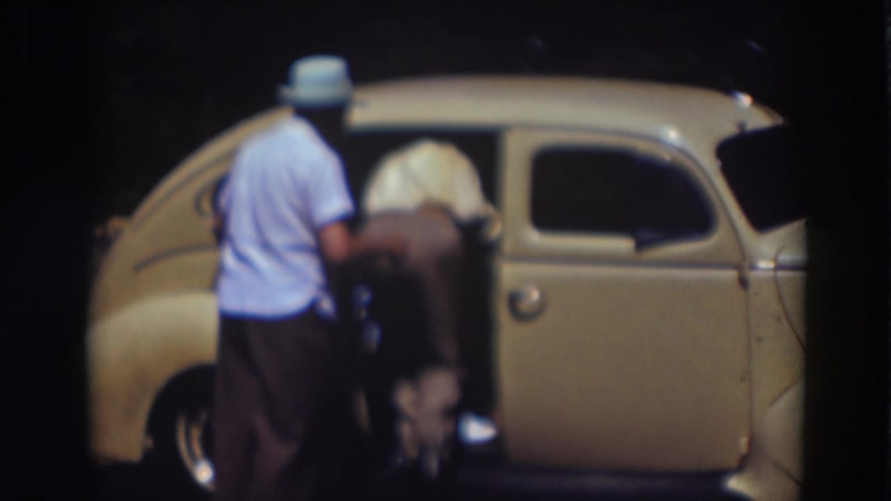 In the Truckee night scene, one man remains outside as another leans into the rear doorway of the cream-colored car.