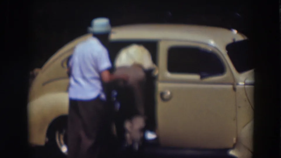 In the Truckee night scene, one man remains outside as another leans into the rear doorway of the cream-colored car.