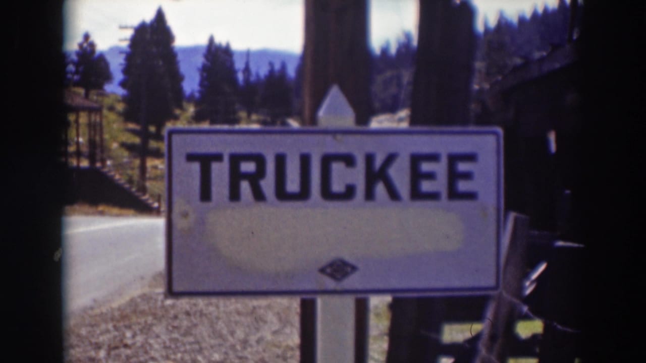 Soft-focus 8mm frame of the TRUCKEE sign along a roadside, backed by trees and a mountain landscape in California.
