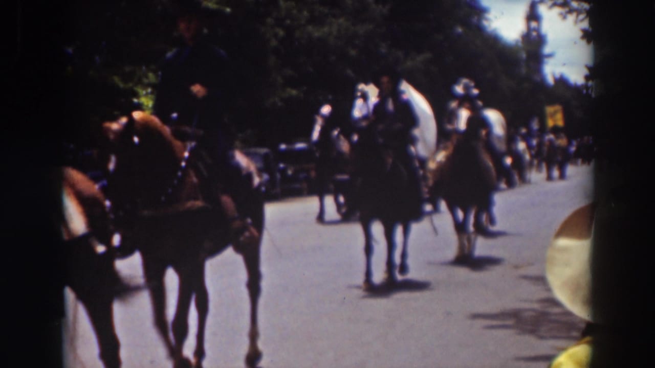 People on horseback ride along a Truckee street during a 1937 parade, with trees, hats, and a few roadside onlookers visible.
