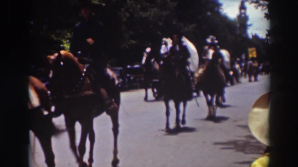 People on horseback ride along a Truckee street during a 1937 parade, with trees, hats, and a few roadside onlookers visible.
