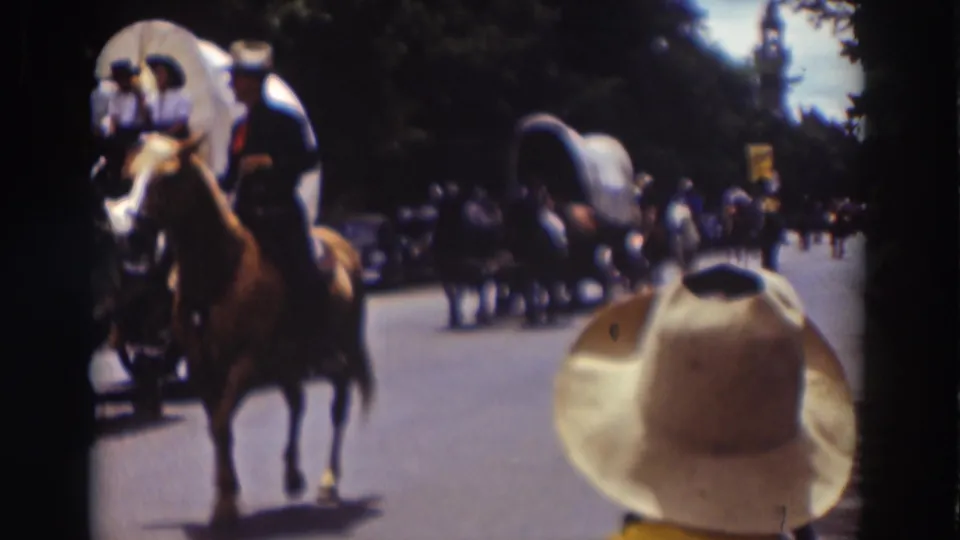 Truckee parade footage from 1937 shows a rider in Western dress near covered wagons, with a large spectator hat at the lower right.