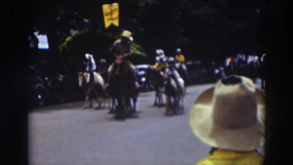 In the 1937 Truckee parade, a rider carrying a yellow flag appears near the front of a group of mounted participants.