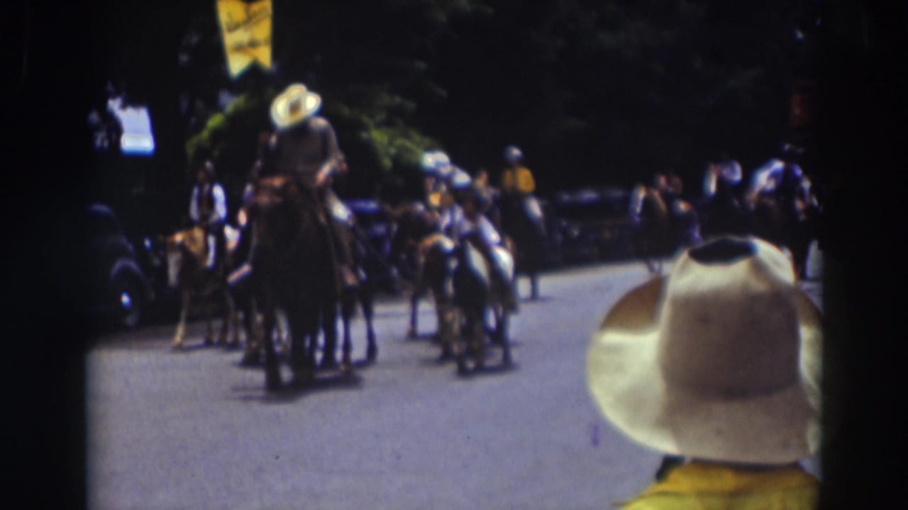 Horseback riders proceed through the Truckee parade while a spectator in a white cowboy hat remains in the foreground of the 8mm frame.